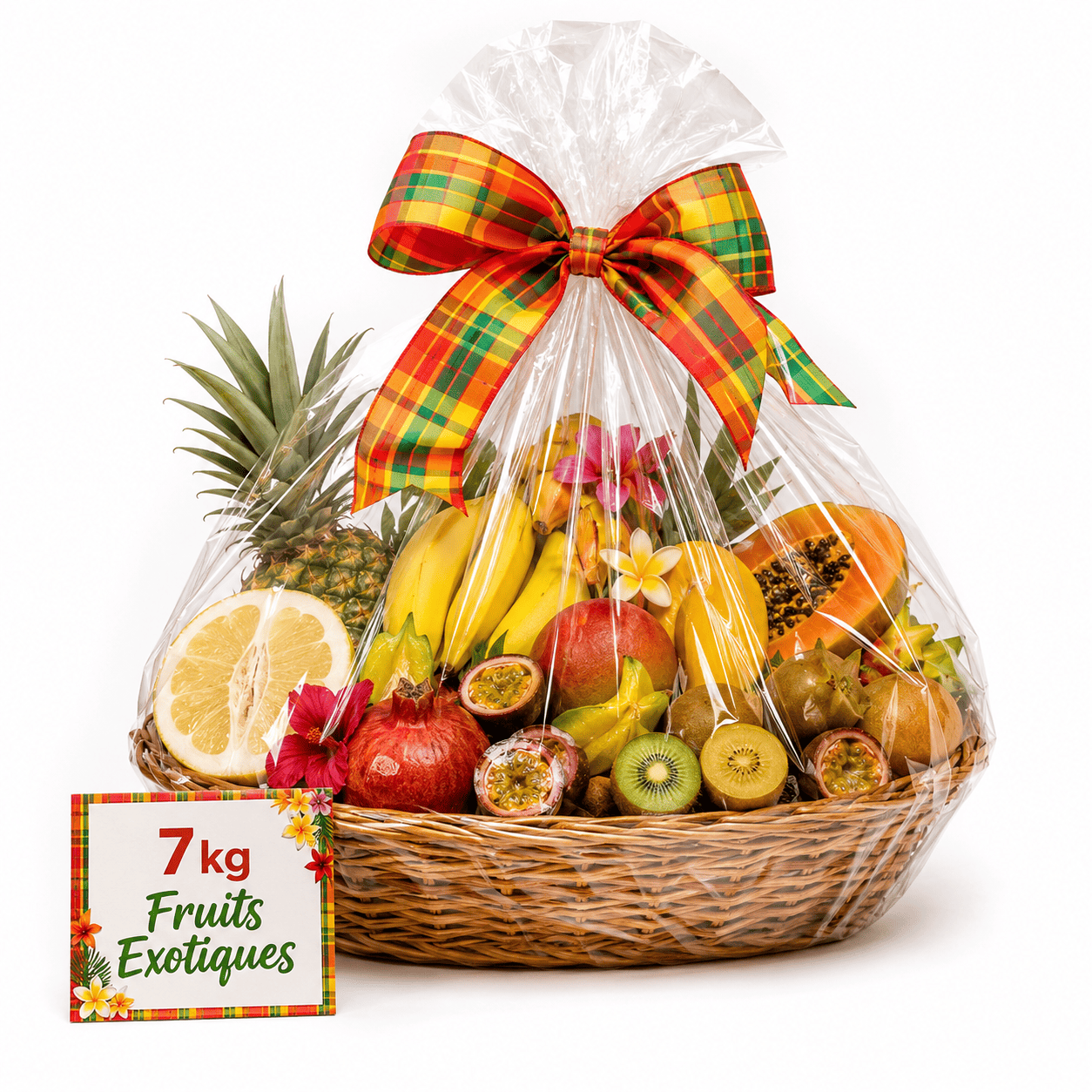 Un panier en osier recouvert d'un film plastique transparent, rempli de fruits exotiques, orné d'un nœud à carreaux et d'une carte sur laquelle on peut lire « CORBEILLE EXOTIQUE 7 KG » au milieu de fleurs colorées.