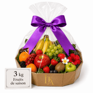 Un panier en carton portant l'étiquette « CORBEILLE DE FRUITS DE SAISON 3 KG », rempli d'un assortiment de pommes fraîches, de bananes, de raisins, d'oranges, de kiwis et de baies, emballé dans du film plastique transparent et orné d'un ruban violet.