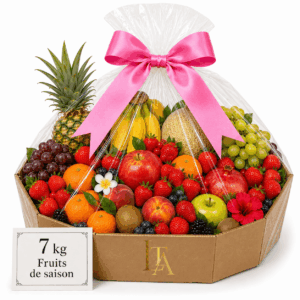 Une grande CORBEILLE DE FRUITS DE SAISON (7 kg) remplie d'un assortiment de fruits frais — ananas, bananes, raisins, pommes, fraises, agrumes et melons —, joliment emballée dans du cellophane transparent orné d'un nœud rose et accompagnée d'une carte portant l'inscription « 7 kg de fruits de saison ».