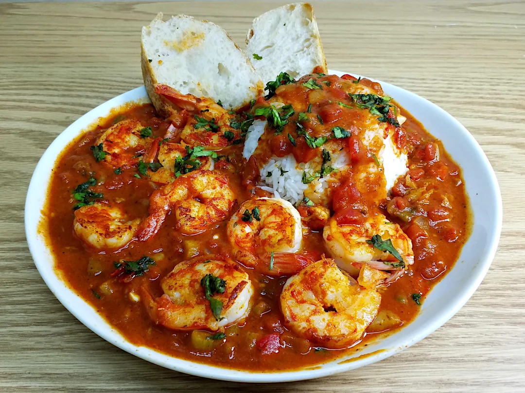 BOUDIN AU CRABE (Barquette de 20 pièces, 40g à l'unité) servi sur une table en bois, accompagné de riz blanc, d'herbes hachées et de deux tranches de pain.