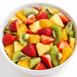 Un bol blanc contenant une SALADE DE 4 FRUITS DE SAISON (250 g) — un mélange coloré de fraises coupées en tranches, de kiwis, d'oranges et de morceaux d'ananas — sur fond blanc.
