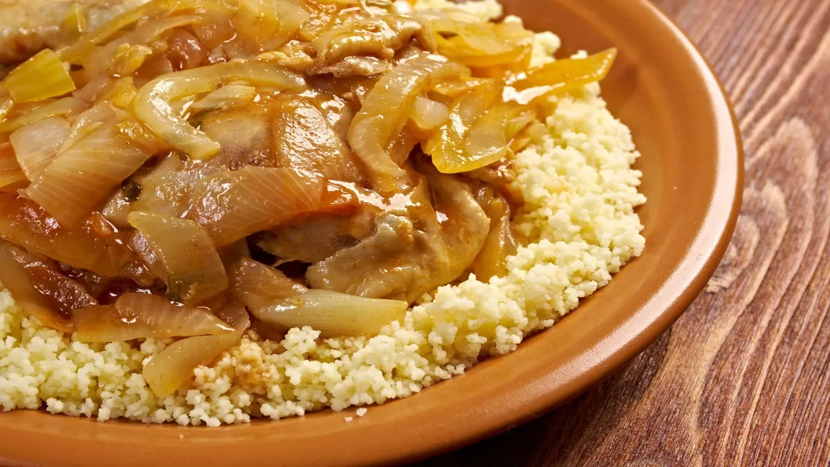 Gros plan sur une assiette contenant du PASTEL DE VIANDE (Barquette de 10 pièces), disposée sur un plat en céramique brune sur une table en bois.
