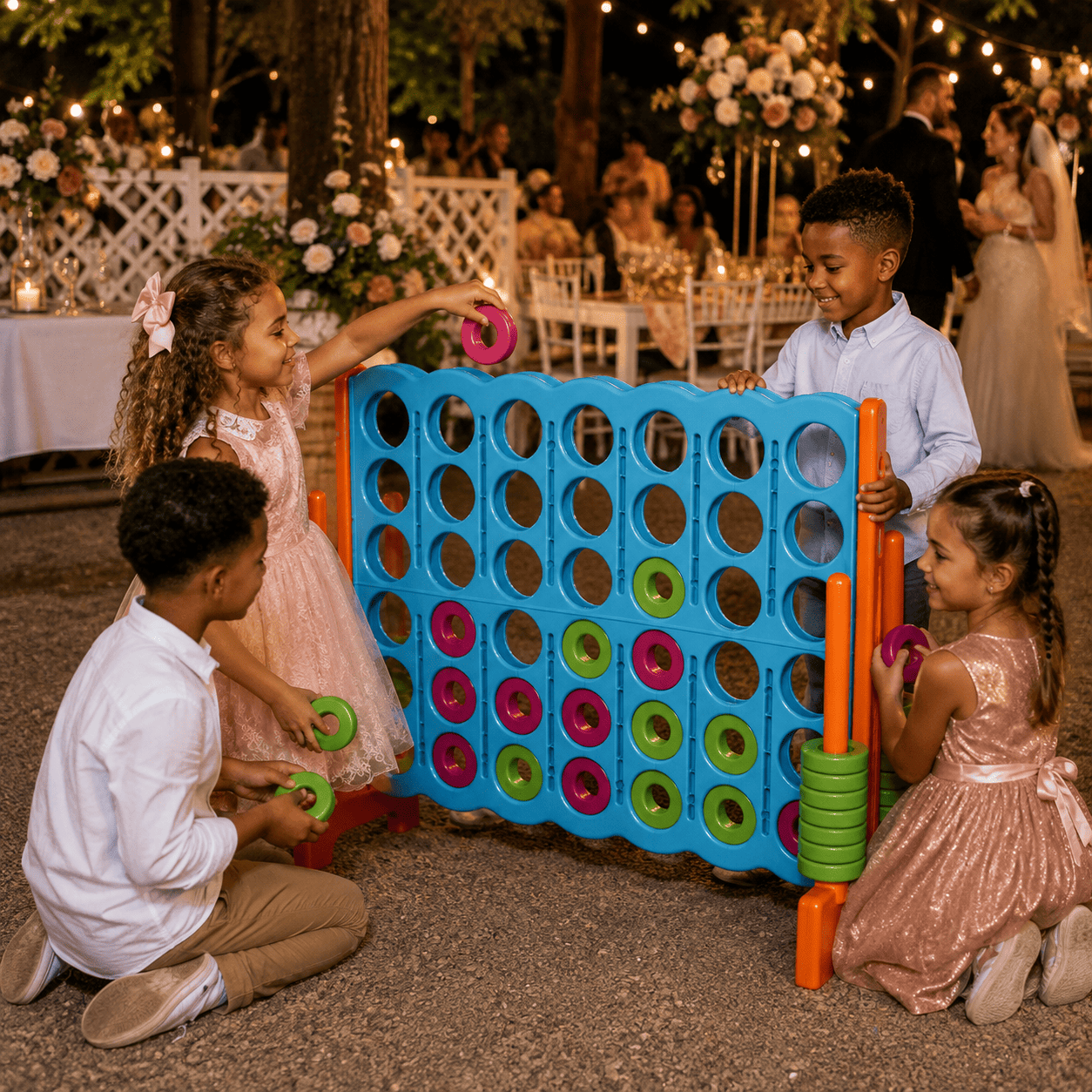 Quatre enfants, sur leur trente-et-un pour une occasion spéciale, jouent au PUISSANCE 4 GÉANT dans un décor festif en plein air, agrémenté de fleurs et de lumières, avec des invités en arrière-plan. Souriant et s'amusant avec les pièces colorées du jeu, les enfants s'amusent ensemble avec cette version géante du Connect Four.