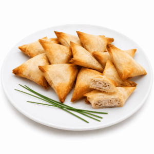 Une assiette blanche présente des SAMOUSSAS AU POULET (commande minimum : 6 pièces) de couleur dorée, de forme triangulaire, dont certaines sont soigneusement empilées et une autre est coupée en deux, dévoilant ainsi sa farce crémeuse au poulet. De la ciboulette fraîche est disposée sur le bord de l'assiette.