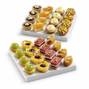Deux plateaux blancs présentent le PLATEAU DE 48 PETITS FOURS TOUT FRUITS, un assortiment de pâtisseries aux fruits de la taille d'une bouchée, joliment disposées en rangées avec des garnitures aux fruits éclatants.