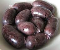 Un bol contenant plusieurs boudins BOUDIN ANTILLAIS 80 GR (commande minimum de 5 pièces) - violet foncé, ovales avec des surfaces brillantes et lisses.