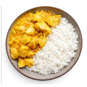 Une portion de COLOMBO DE POULET (entrée + plat - pour 6 personnes minimum) est servie dans une assiette ronde, avec du riz blanc d'un côté et du poulet au curry jaune de l'autre.