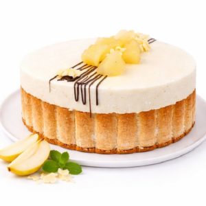 Le CHARLOTTE POIRE CHOCOLAT (10/12 parts) est un gâteau rond bordé de doigts de dame, garni de morceaux d'ananas, d'un filet de chocolat et de copeaux de chocolat blanc. Des tranches de pommes et des feuilles de menthe sont disposées à côté sur une assiette blanche.