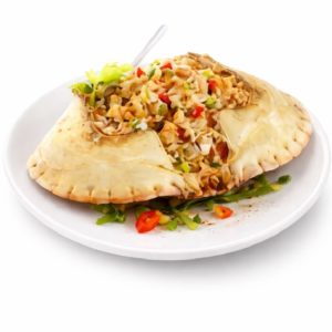 CRABE FARCI À L'ANTILLAISE (calibre 11cm, minimum 5 pièces) est servi dans une assiette blanche avec une carapace de crabe remplie de riz frit, garnie de légumes hachés et de tranches de piment rouge. Une cuillère repose dans la carapace pour faciliter le service.