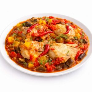 Une assiette blanche contient des MIJOTÉS DE POULET AUX LÉGUMES ET BANANES FRITS (300g), des cuisses de poulet dans une sauce à base de tomates avec des poivrons jaunes et rouges, des aubergines, le tout agrémenté de piments rouges et d'herbes fraîches.