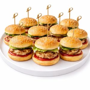 Un plateau blanc présente neuf MINI CHEESEBURGERS (25g/chacun), chacun sur un petit pain au sésame avec de la laitue, de la tomate, du fromage, et fixé avec un cure-dent décoratif. Commande minimum : 20 pièces.