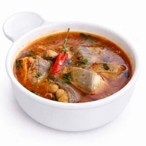 Un bol de PÉPÉ SOUPE (300 g) rempli d'un ragoût de poisson épicé, composé de morceaux de poisson, d'herbes hachées et d'un piment rouge entier dans un bouillon riche et rougeâtre.