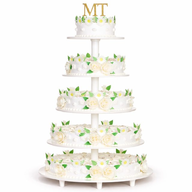 Le PIÉCE MONTÉE BELLA ROSA 50 PARTS est un gâteau blanc à six étages orné de roses blanches, de marguerites, de feuilles vertes sur chaque étage, et terminé par les initiales dorées MT, présenté sur un support à étages blanc.