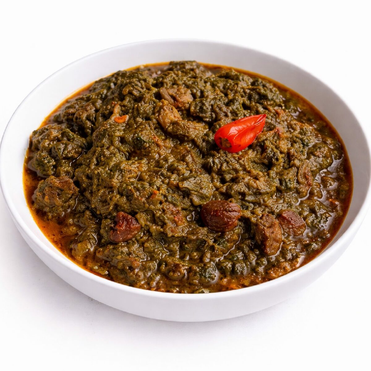 SAKA SAKA (300 g) : Un bol blanc contient un épais ragoût vert foncé et brun surmonté d'un piment rouge entier, mettant en valeur de copieux morceaux de viande et de légumes.
