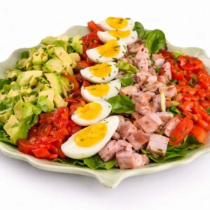 SALAD COMPOSÉE (Minimum de commande de 5 pers/200g/) : salade en rangées avec avocat, tomates, œufs durs, jambon cuit en dés et jeunes pousses, le tout parsemé d'herbes aromatiques.