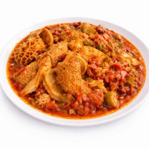 Une assiette blanche de TRIPES À LA SAUCE TOMATE (300 g), composée d'un assortiment de viandes comme les tripes et le poulet dans une sauce tomate rouge riche et épicée avec des légumes hachés.